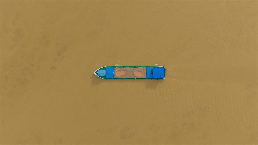 Drone view of a boat on the brown water of the Mekong at Phnom Penh